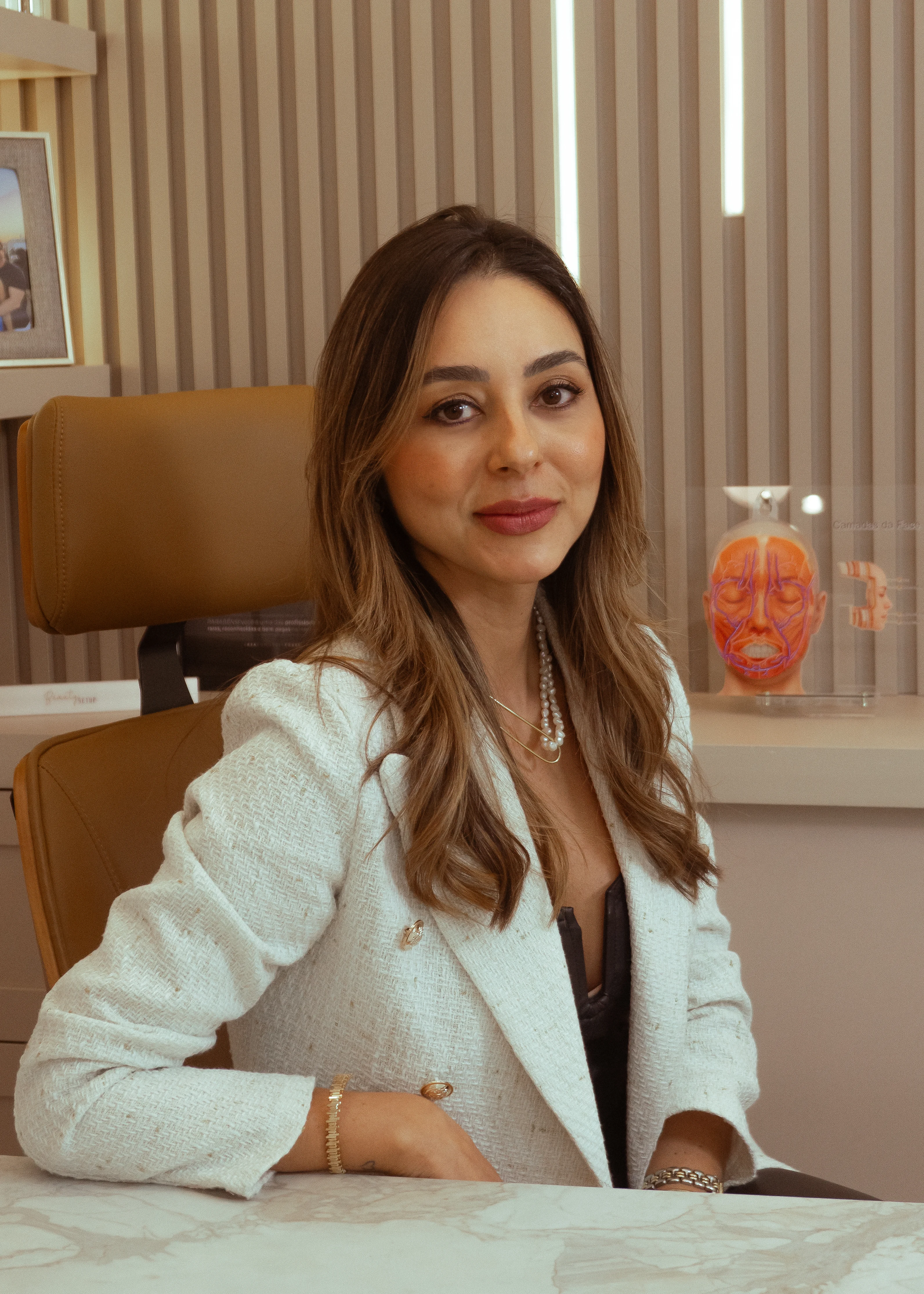 Dra. Ana Carolina Prata no consultório com modelo anatômico facial