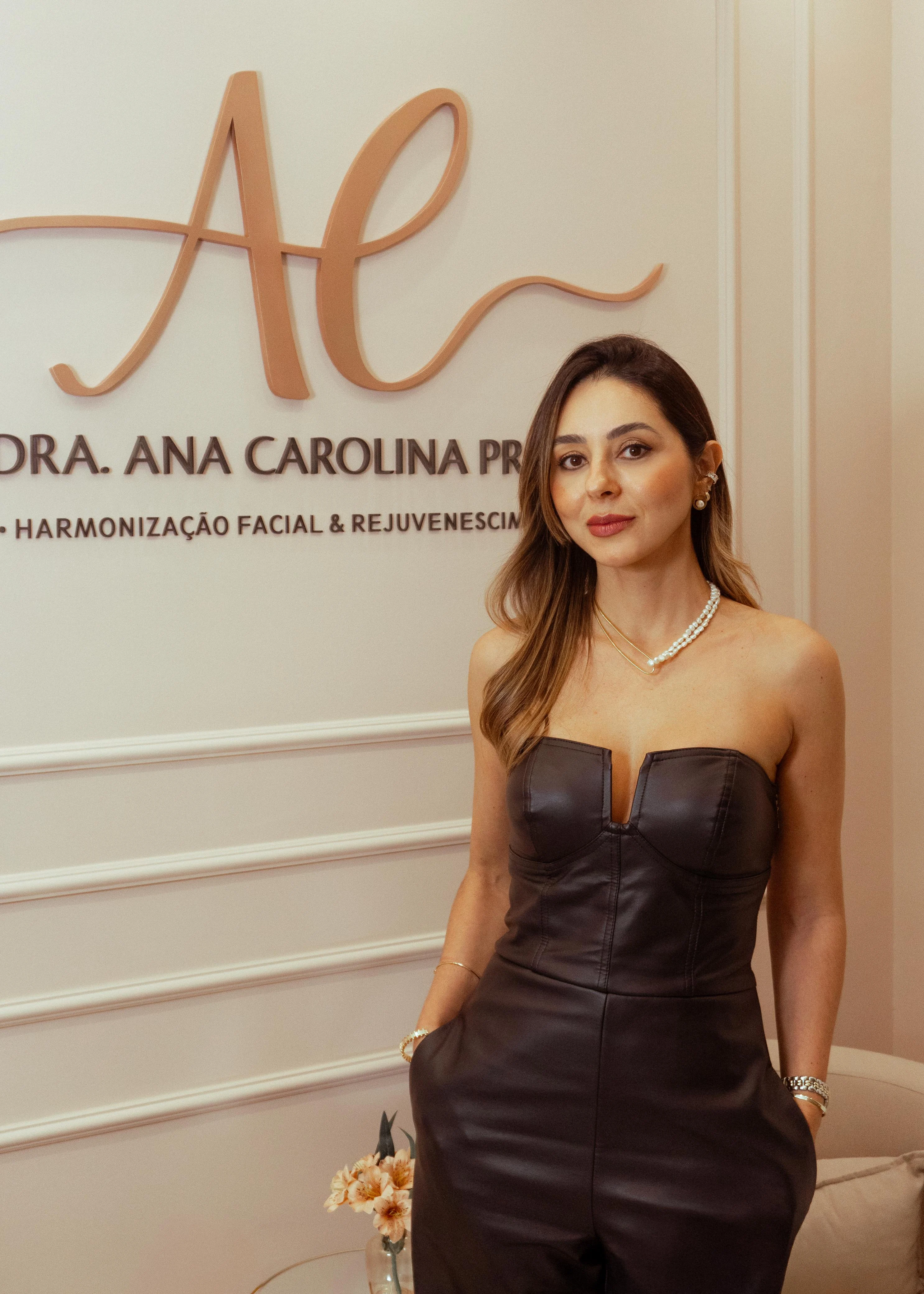 Dra. Ana Carolina Prata em frente ao logo da clínica em rose gold